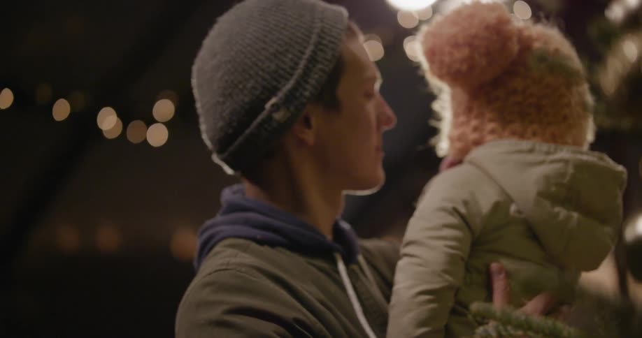 A man holds a toddler outdoors at night