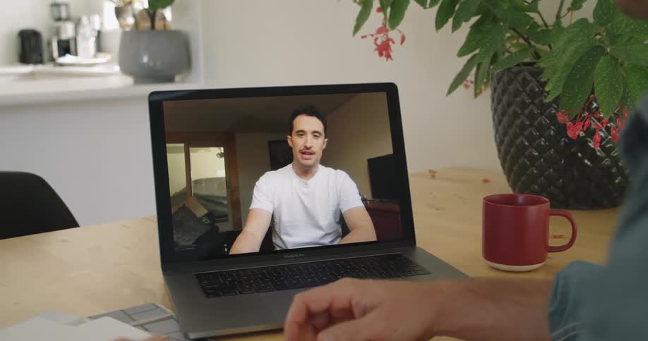 Men have video meeting via laptop to discuss paper diagrams