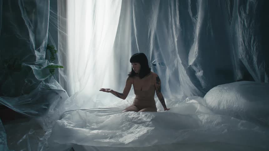A model looks at her hand as she poses on plastic sheets
