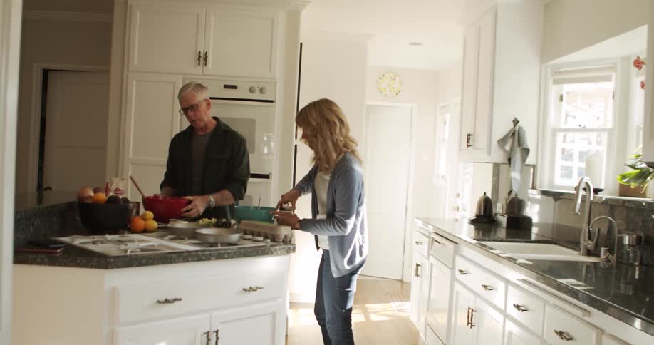 A man and woman working together cooking food