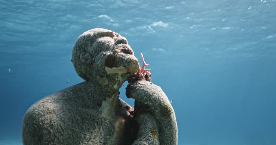 Close up of a statue submerged underwater near the bahamas in the clear blue ocean water