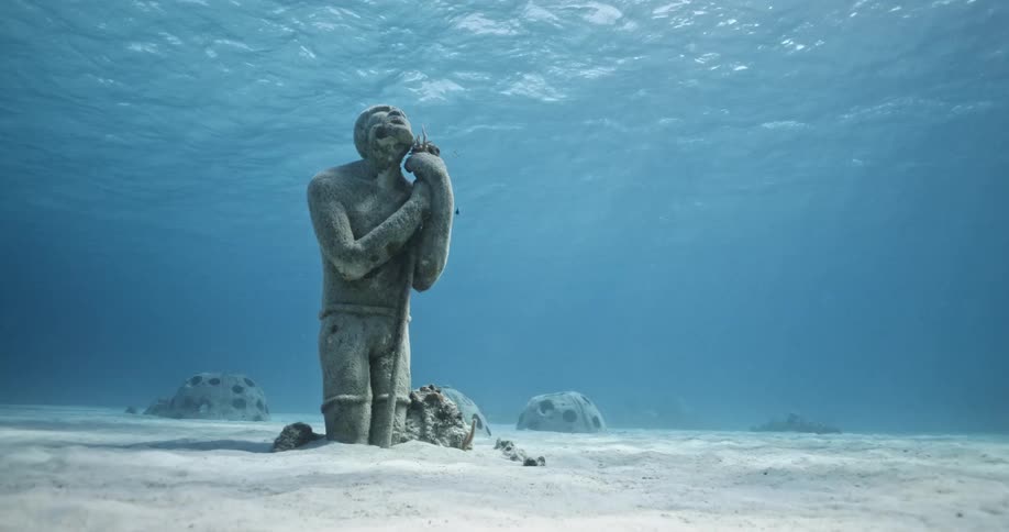 The sunlight shines through the ocean on the underwater sculpture