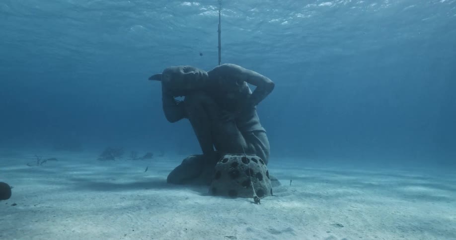 A statue underwater in the ocean with sand