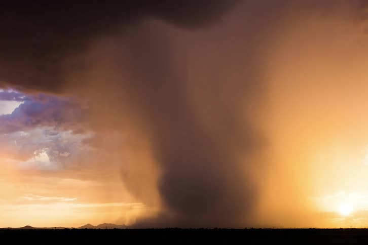 Storm clouds over a field with rain falling