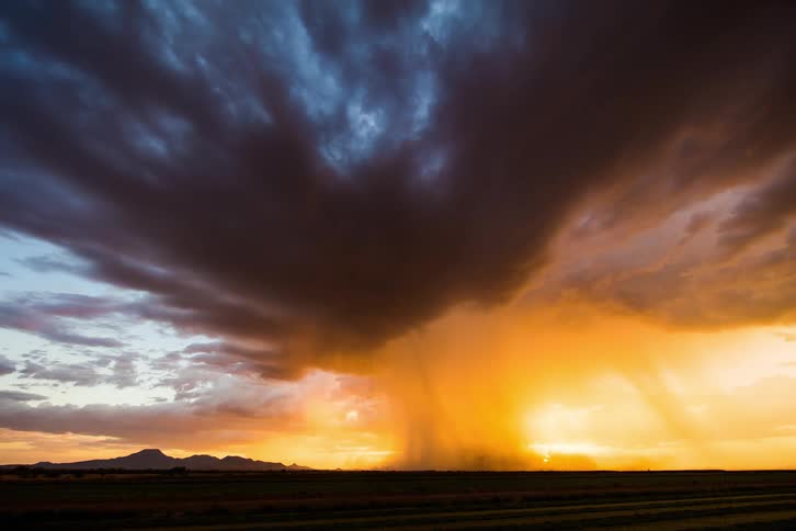 Dark storm clouds and rain at sunset