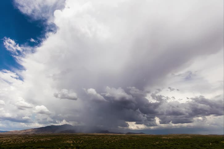 Clouds are moving fast in the sky above a field