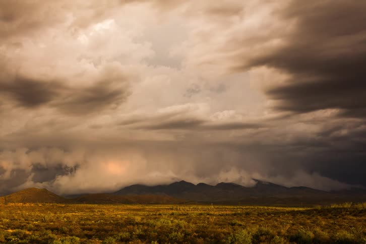 A storm forming over a field and hills