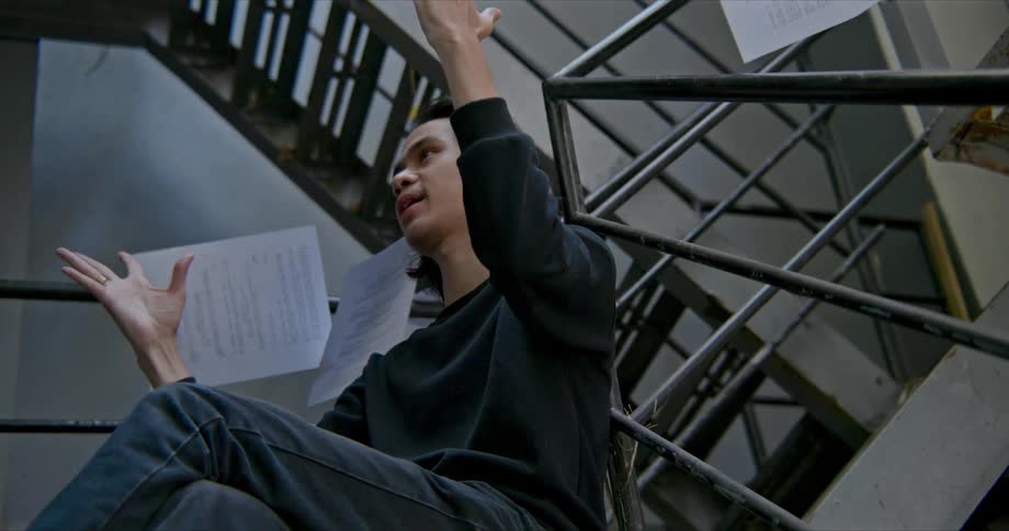 A man throwing papers in a stairway