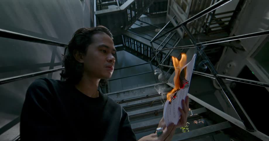 A man sitting in a stairway burning paper