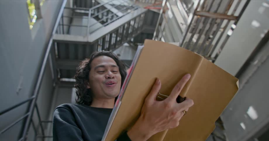 A teenage boy reads and laughs in a stairwell