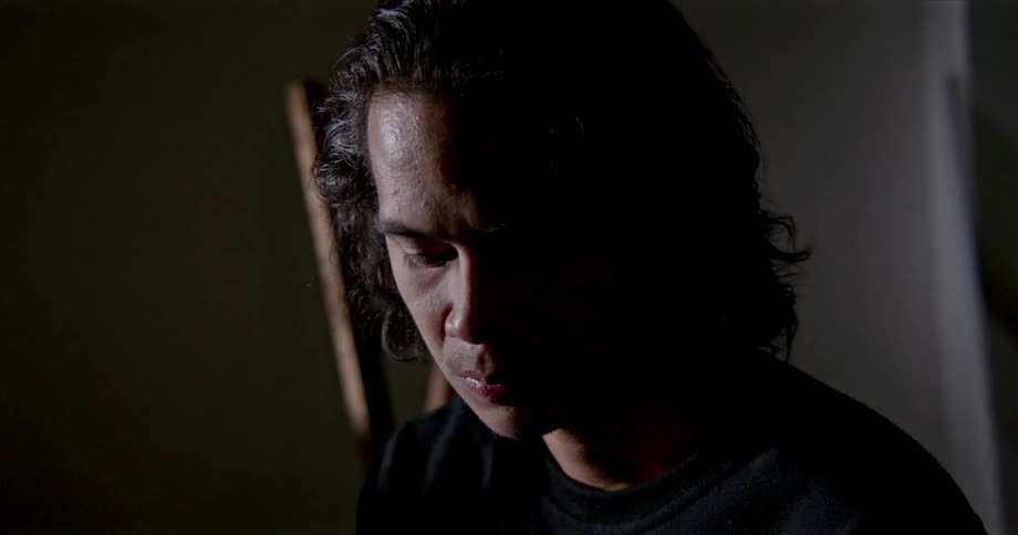 A man looks downward as he is lost in thought and shadows pass over him