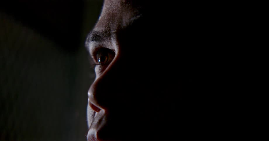 A man in a room staring off into the distance with a wall in the background