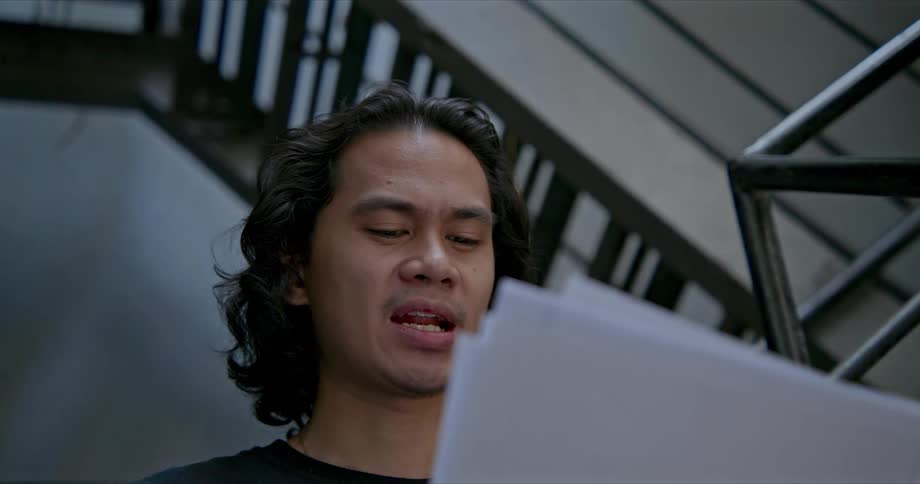 A man in a room with papers sitting on a staircase with a wall in the background