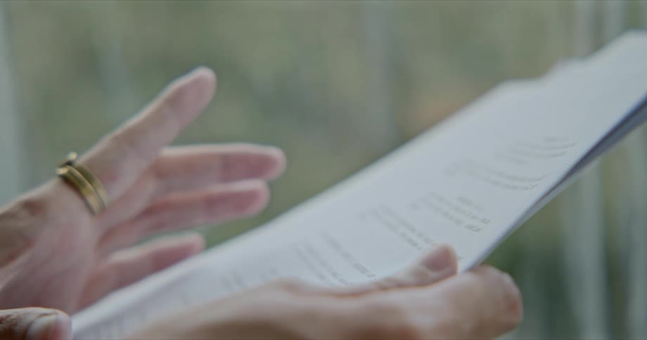 A person waving hands over a printed document while reading
