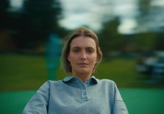 A woman in a merrygoround staring with trees the sky and clouds in the background
