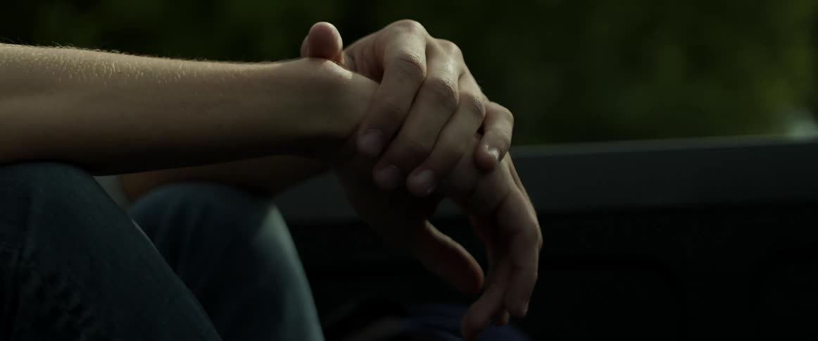 Person clasps hand over hand while riding in truck bed