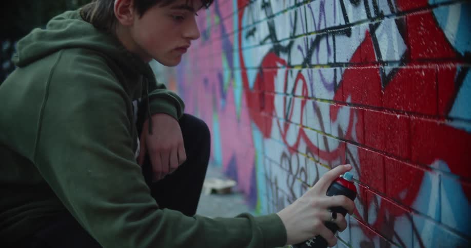 A man spray painting a block wall outside