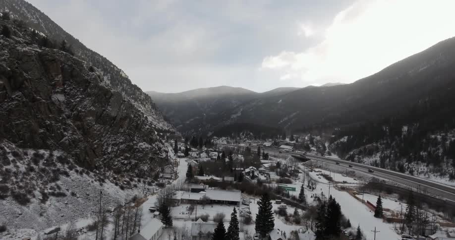 Aerial view showing a town and cars driving near mountains
