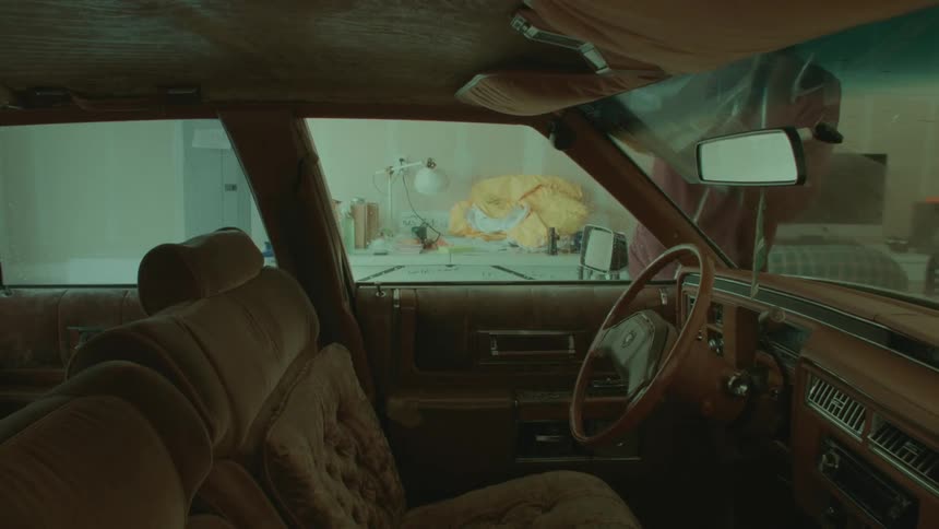 A view of a person wiping off a cars windshield in a garage