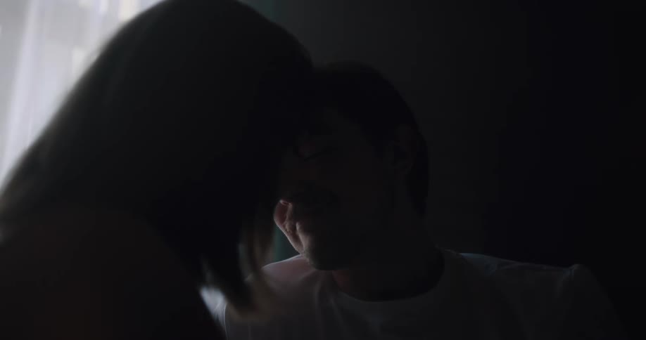 A man leans forward to gently kiss his female companion