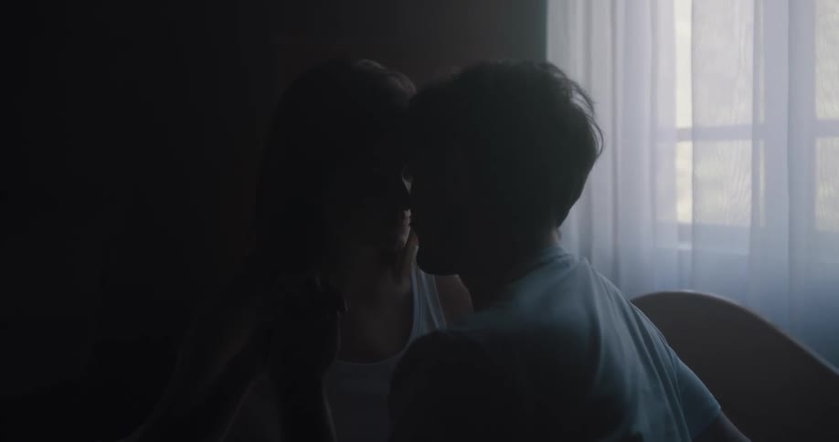 Husband and wife are kissing while in their bedroom