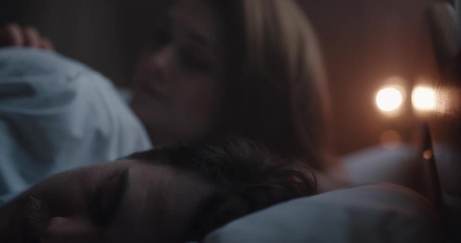Husband and wife are sleeping on their bed indoors