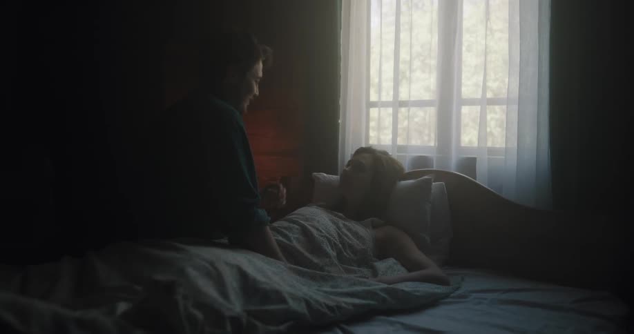 Husband and wife are sitting on their bed indoors