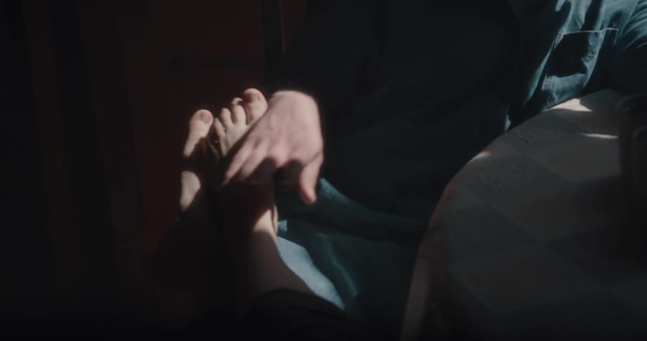 A woman puts her feet in a mans lap and he caresses them