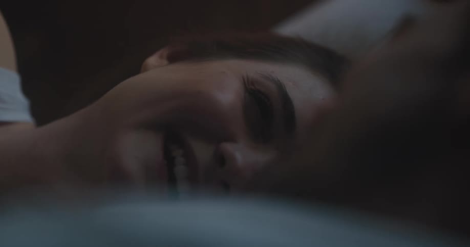 Woman laughs lying next to man on bed