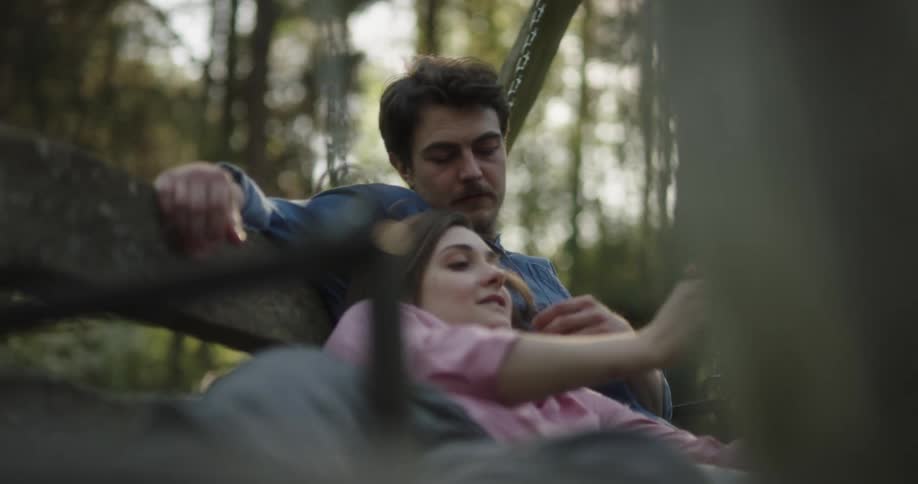 A man and woman cuddle and talk on a porch swing