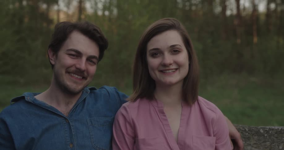 Man and woman are sitting outdoors together at dusk