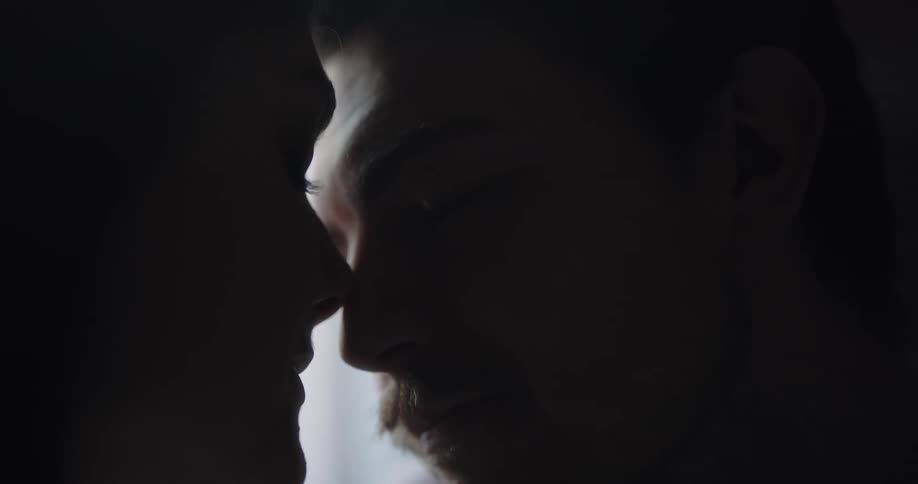 A woman strokes a mans face as they put their heads together and look into one anothers eyes
