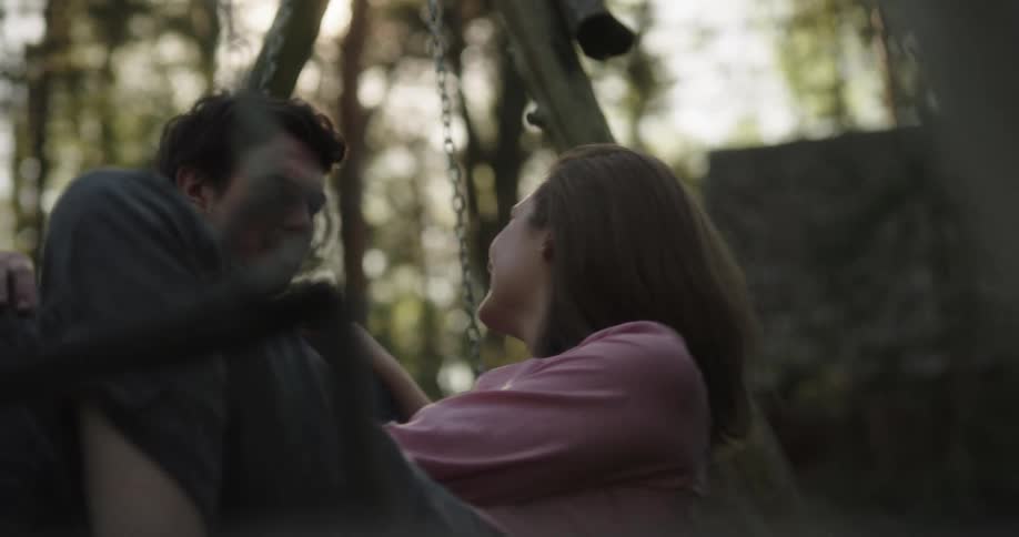 Man and woman are outdoors on a swingset