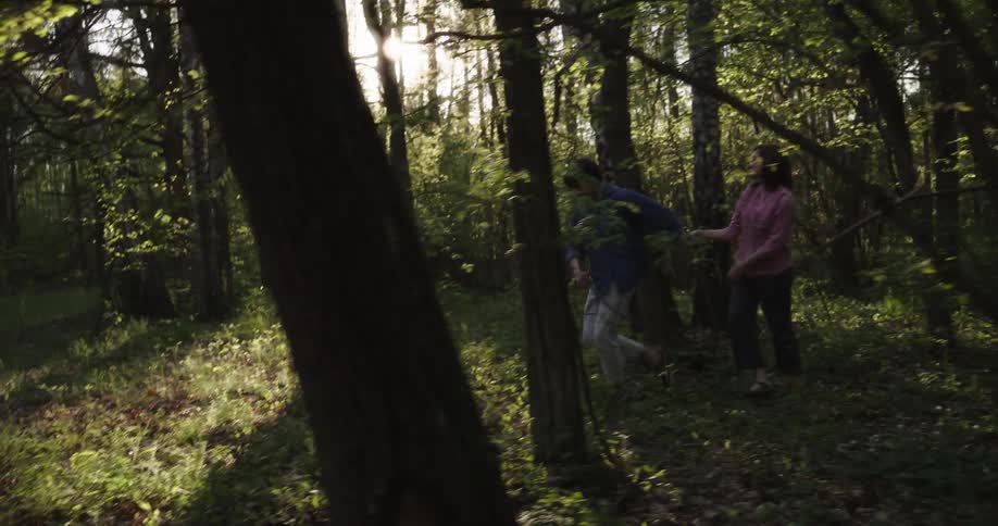 Couple walks through woods as sun shines through trees