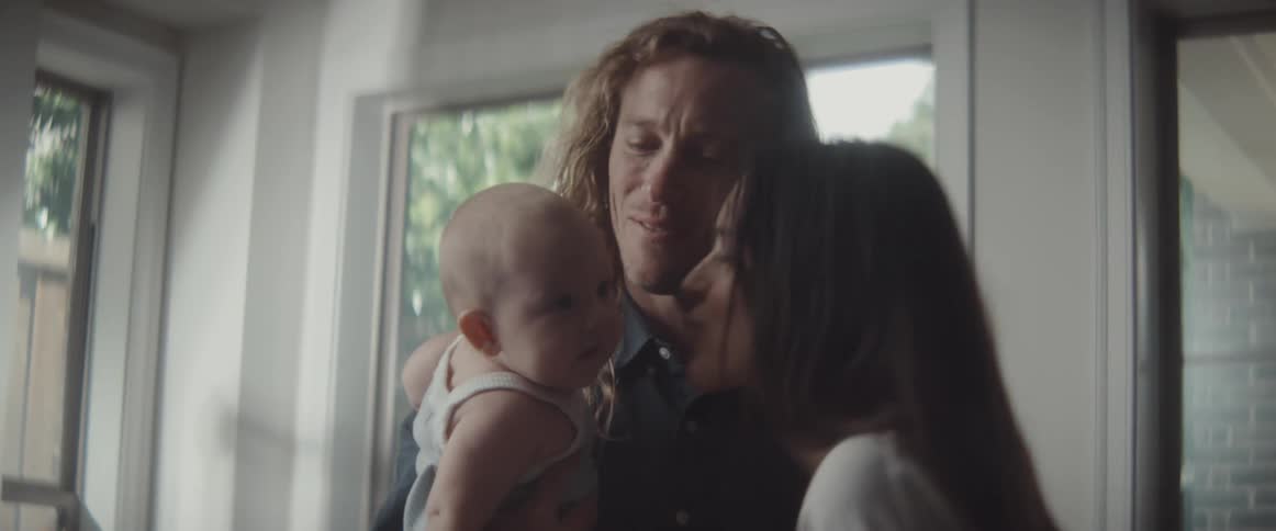 Mother and father play with baby standing near windows