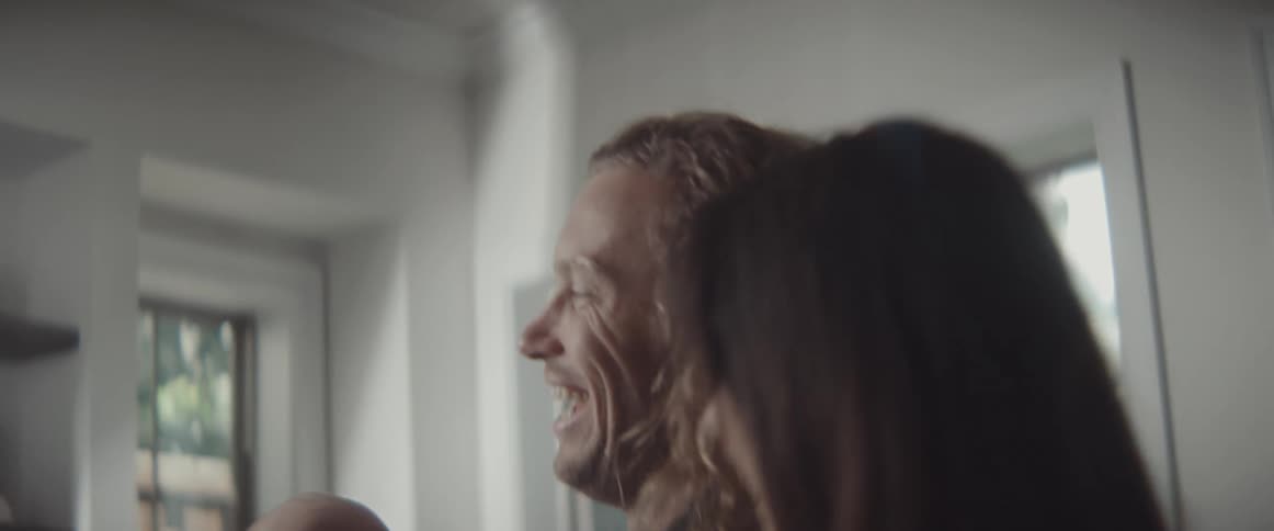 A man and woman laugh as the man lifts his baby in to the air