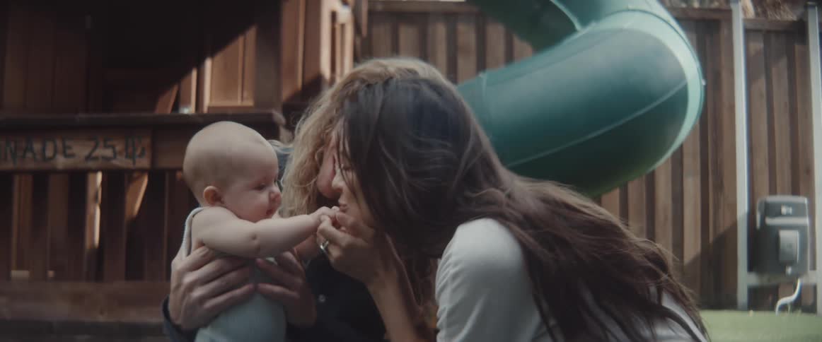Parents play with baby smiling and laughing while outside in yard