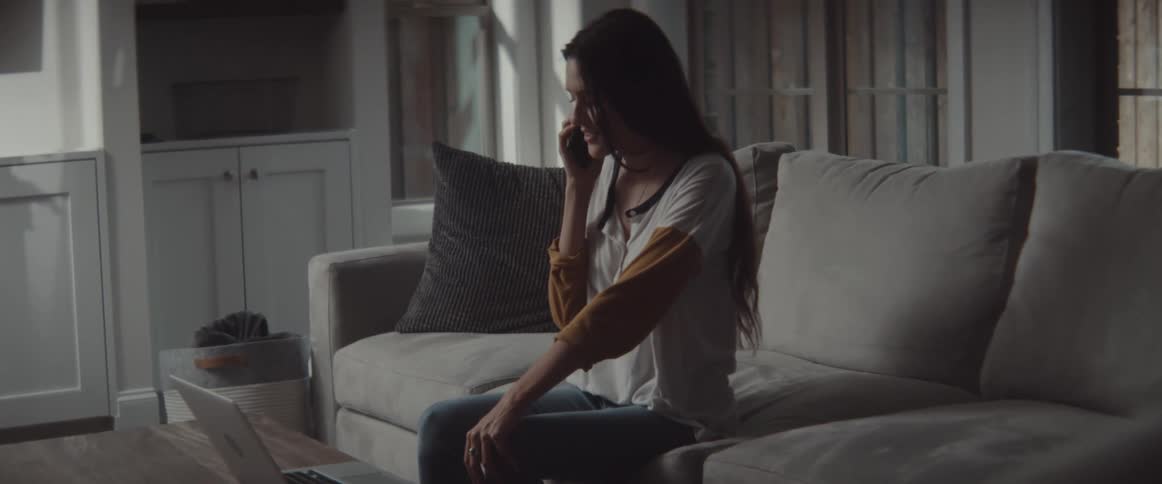A woman talks on her cell phone on the couch