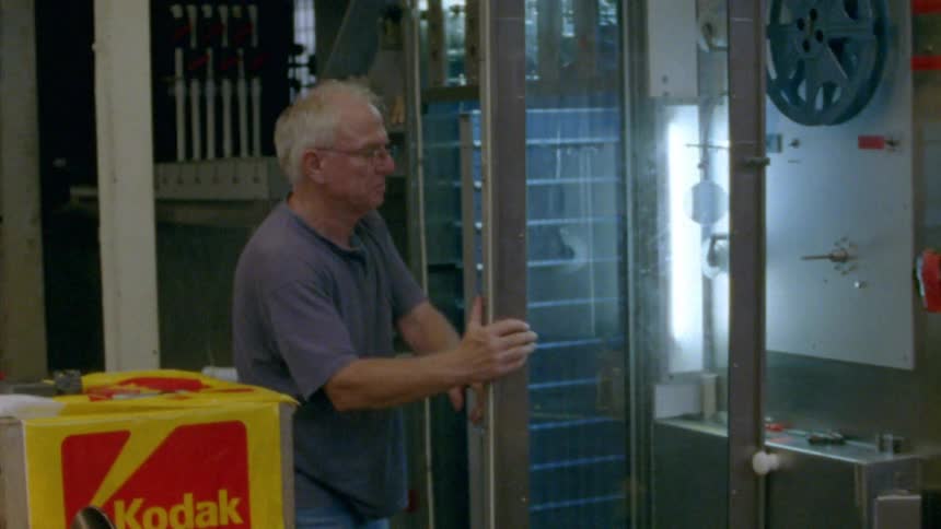 A man opens a glass door and adjusts reels of film