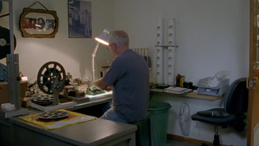 A man sits at large table working in a workshop