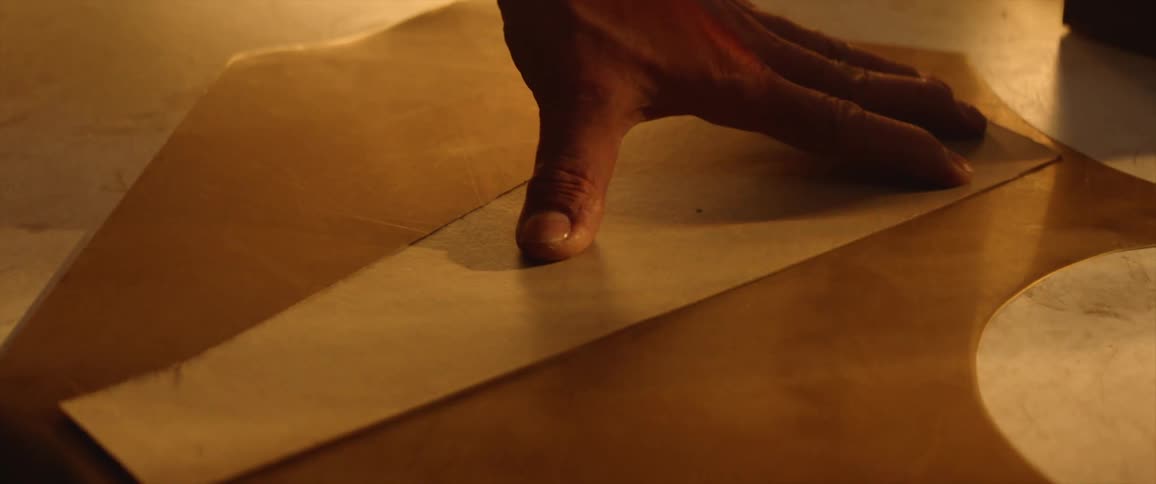 Hands place a pattern on material then cut along the guide