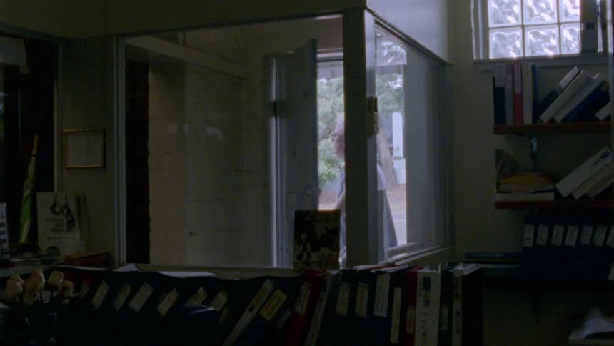 An elderly man walks out the door of a store