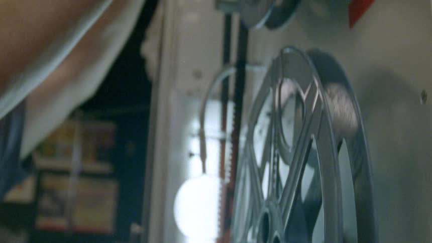 A man with glasses cutting a strip of film with a scissors