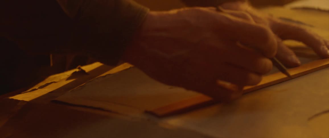 Person traces line using ruler on top sheet of paperboard