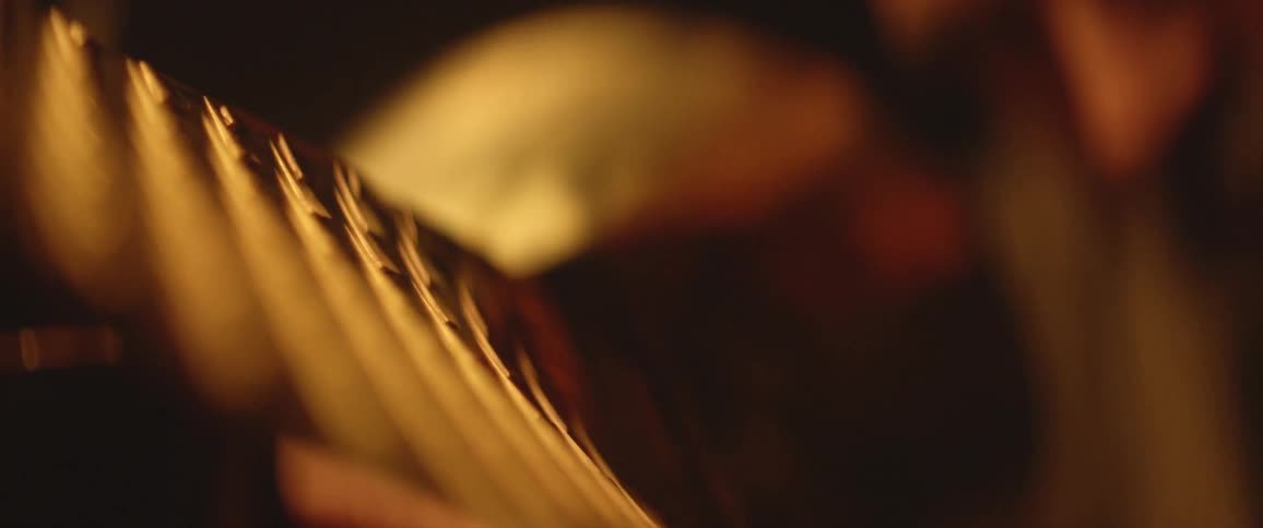 Person touches golden metallic object with textured surface pattern