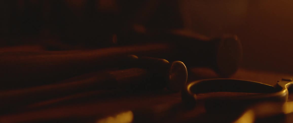 Set of hammers resting over a workbench inside a dimly lit room
