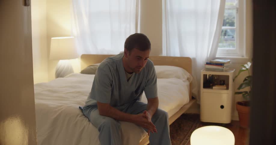 A man looking upset sitting on his bed