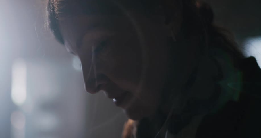 Woman wearing hair tie looks side lit by light looks up and leans forward