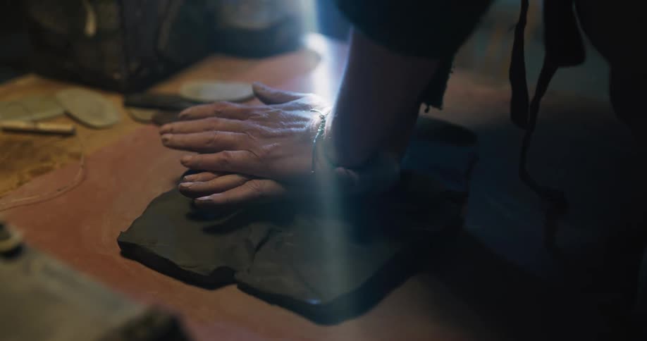 A woman kneads clay