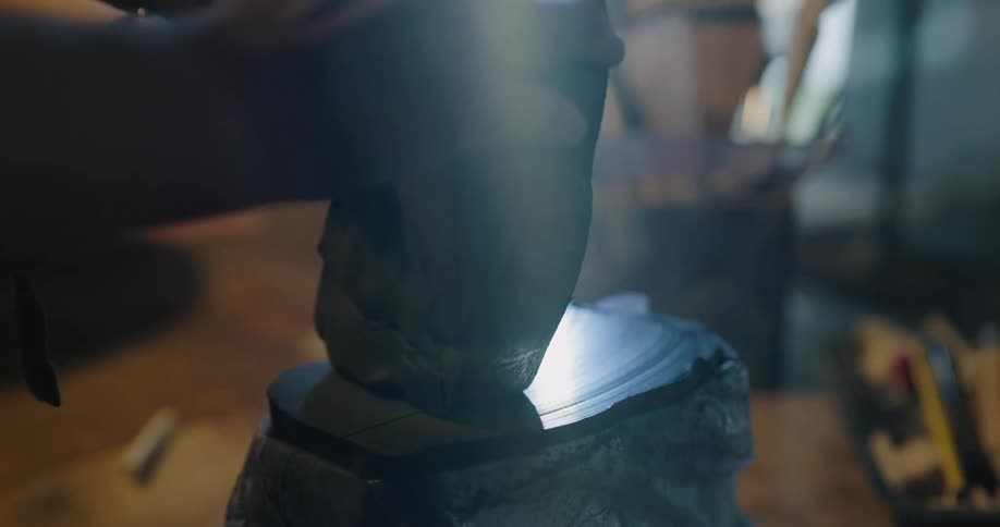 A person in a room cutting a piece of clay on a table with a string with a window in the background